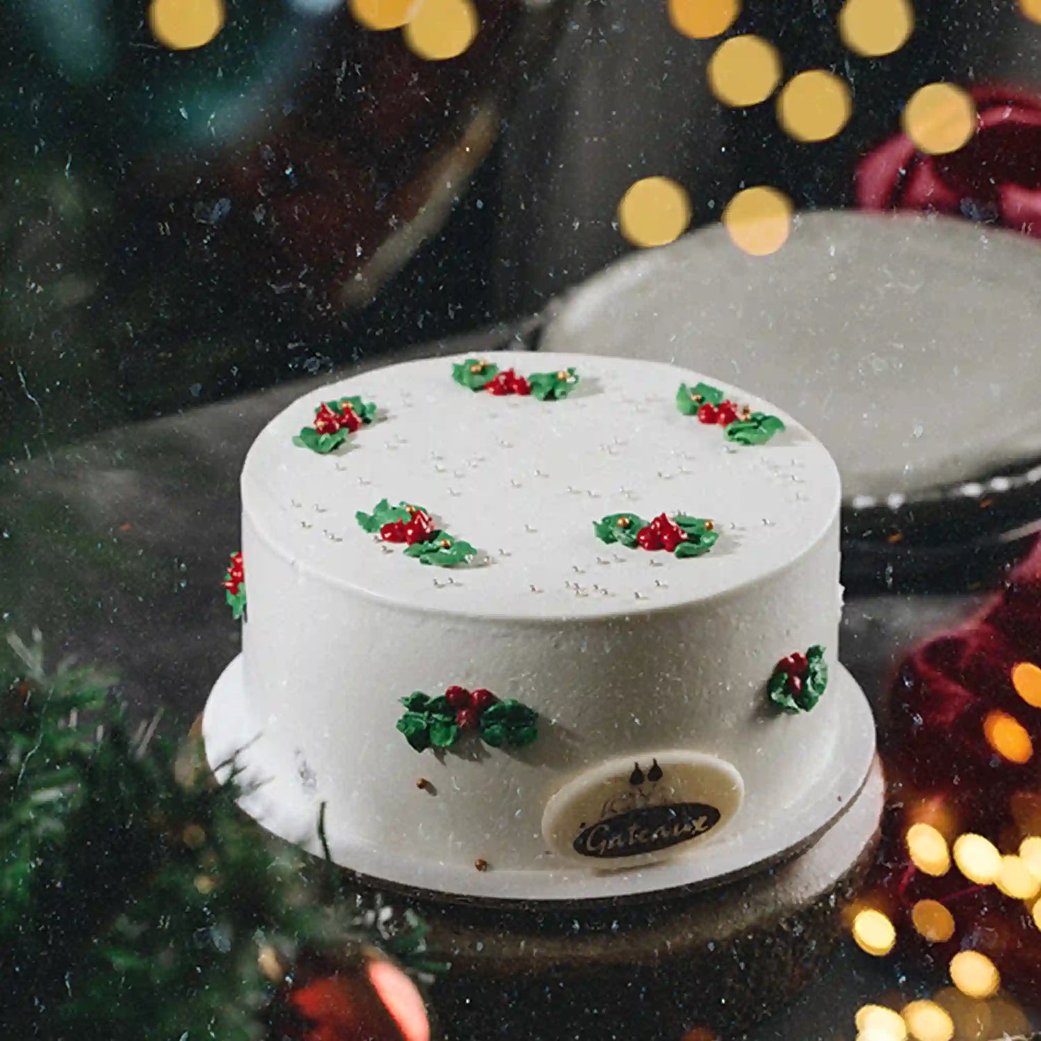 White cake with green and red decorations on a blurred festive background
