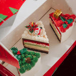 Two slices of Christmas-themed cake in a decorative box