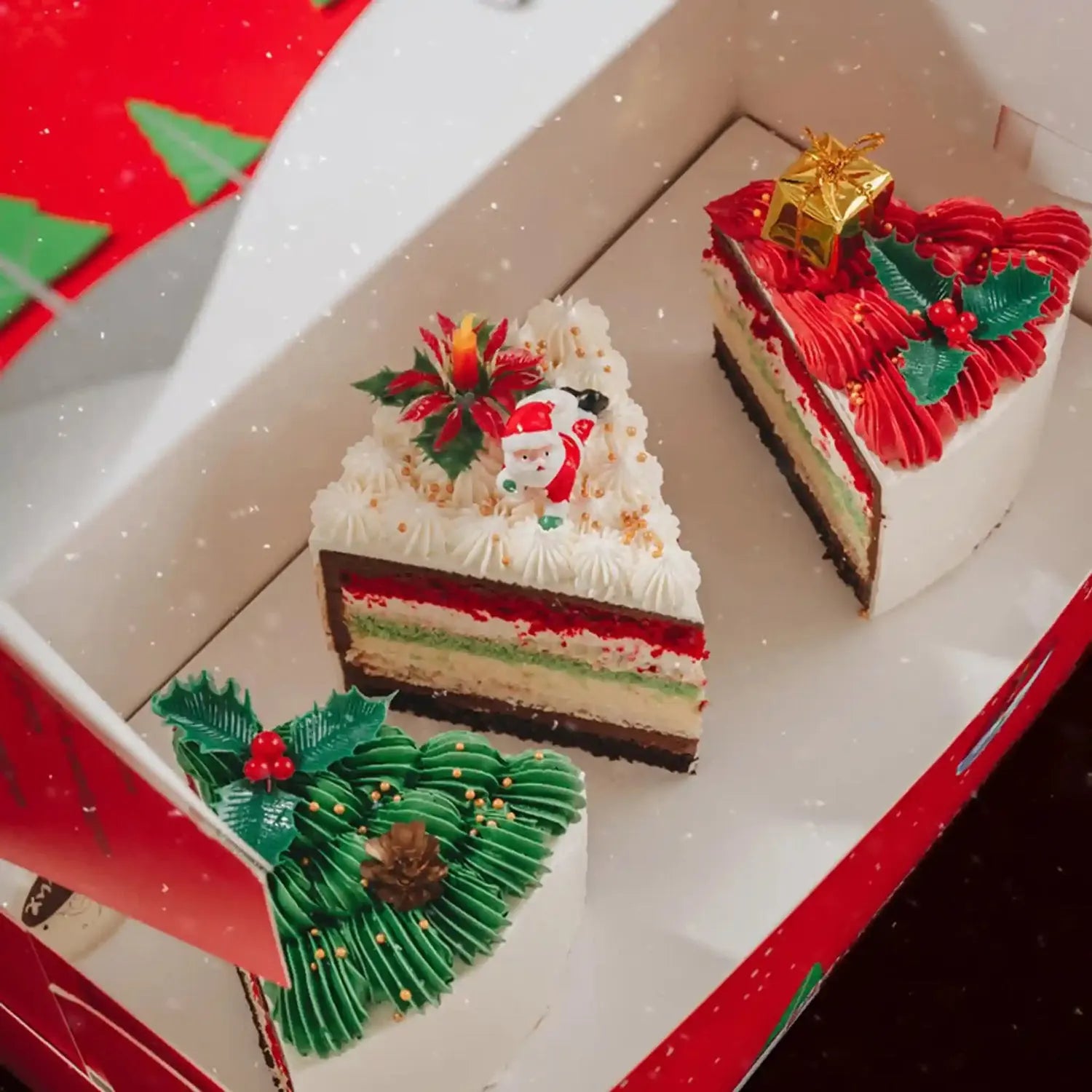 Two slices of Christmas-themed cake in a decorative box