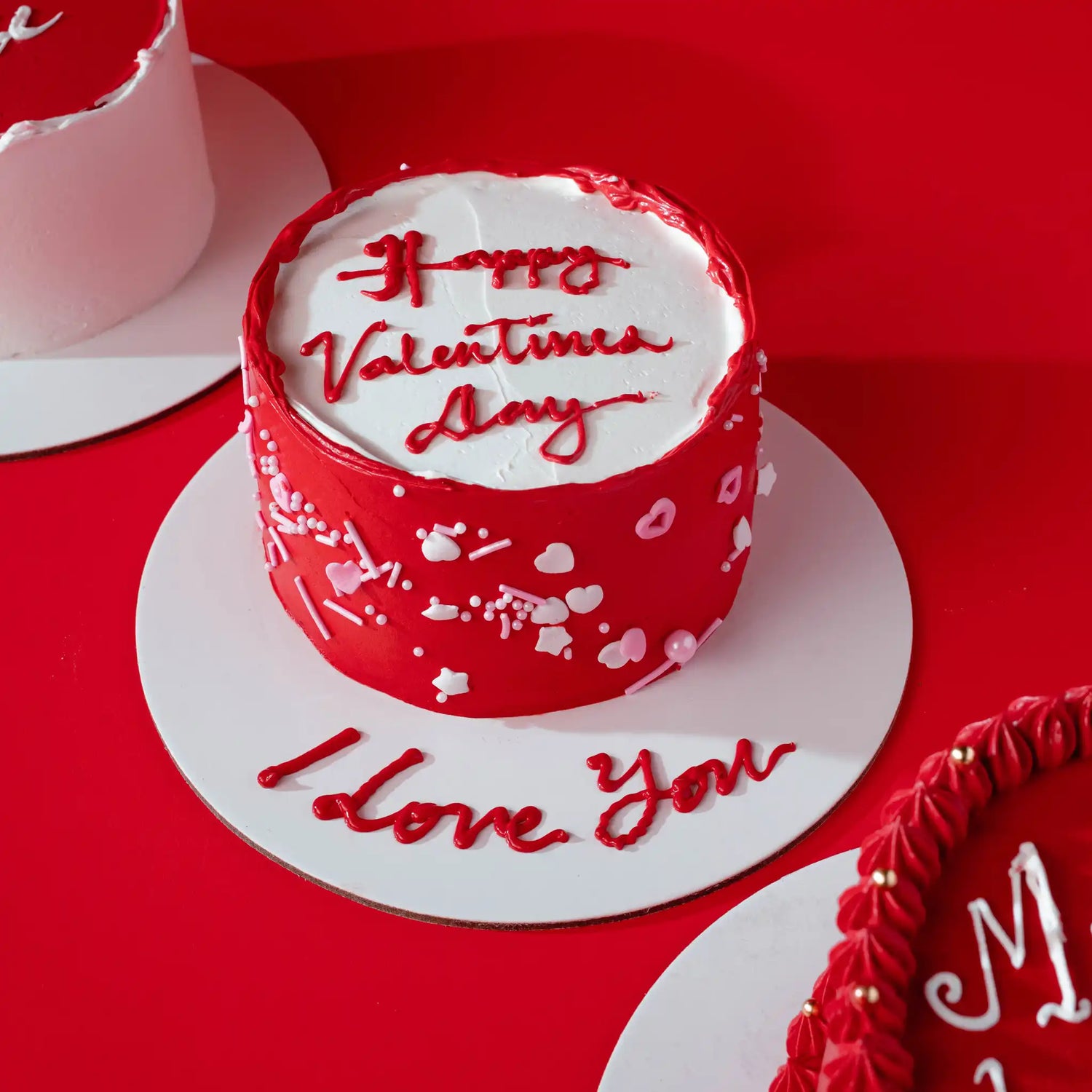 Red and white Valentine's Day cake with 'Happy Valentine's Day' and 'I love you' text on a red background.