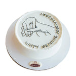 Round cake with 'Happy Wedding Anniversary' text and hand holding a ring illustration on a white background.