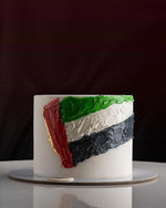 Cake with a design resembling the flag of Palestine on a white surface.