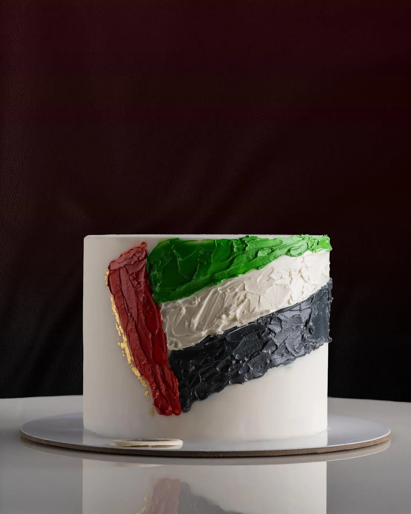 Cake with a design resembling the flag of Palestine on a white surface.