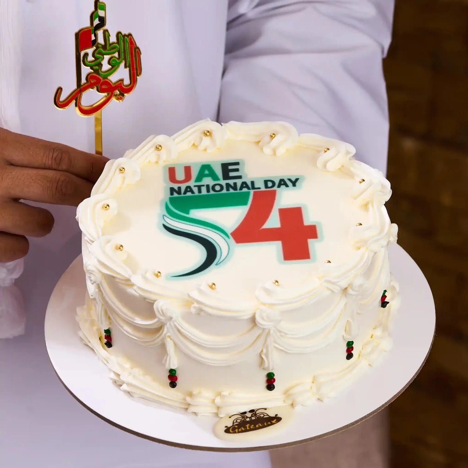 Cake celebrating UAE National Day with decorative elements on a white plate.