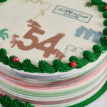 Decorative cake with green icing, red berries, and a number '54' on a white background.