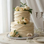 Two-tiered white wedding cake with floral decorations on a table.