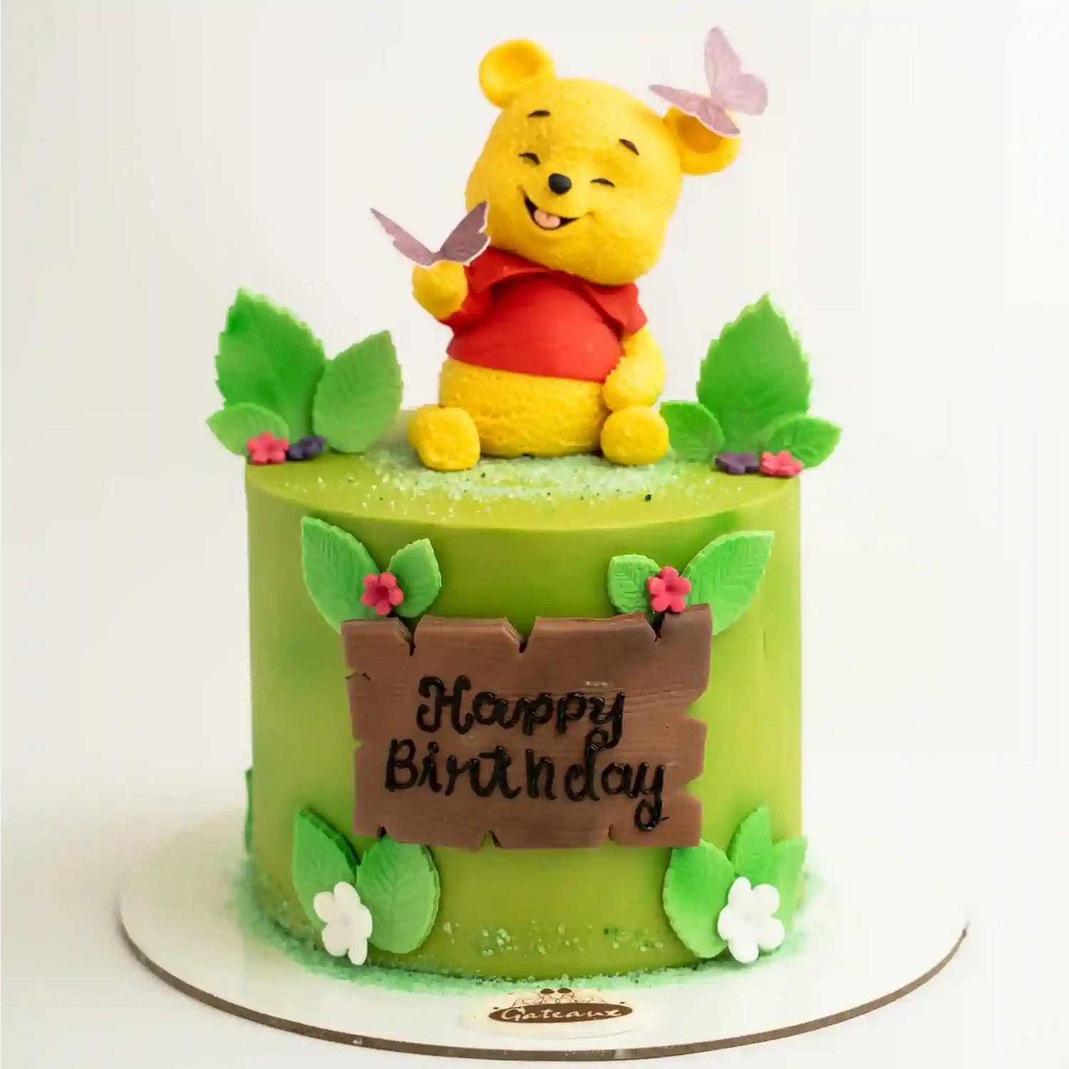 Green birthday cake with a Winnie the Pooh figurine on top