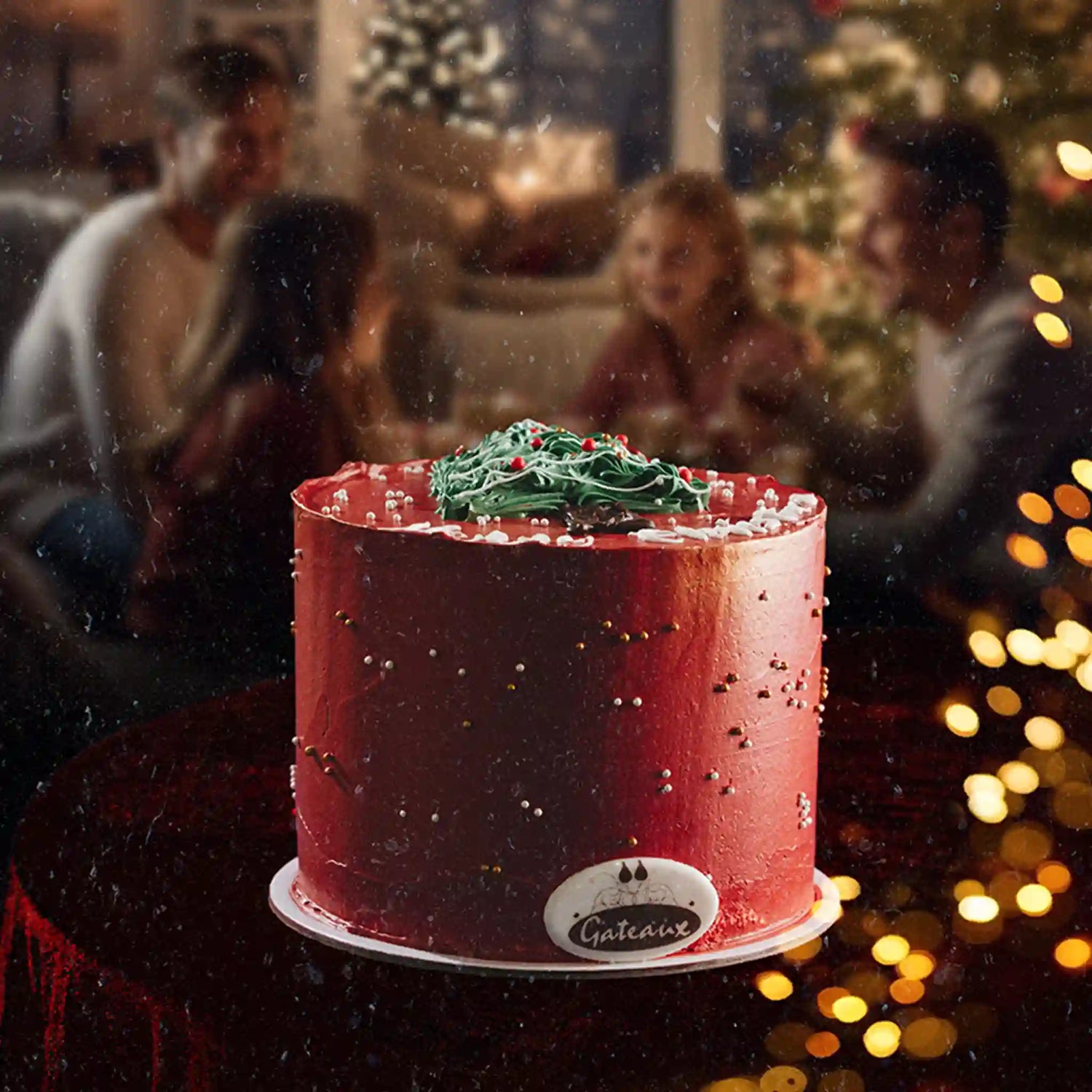 Red cake with green frosting in a festive setting with blurred people and lights.
