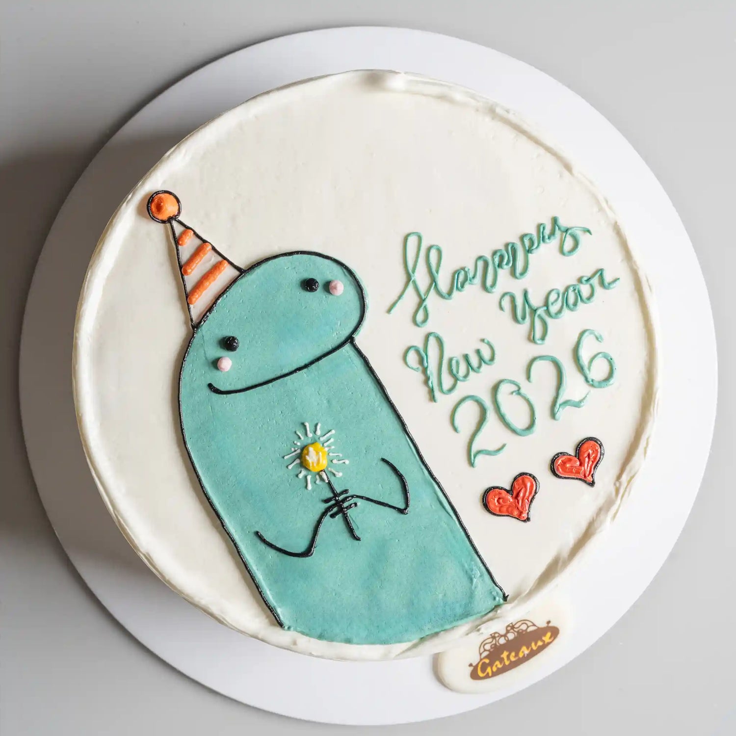 New Year's themed cookie with a blue creature, party hat, and text on a white plate.