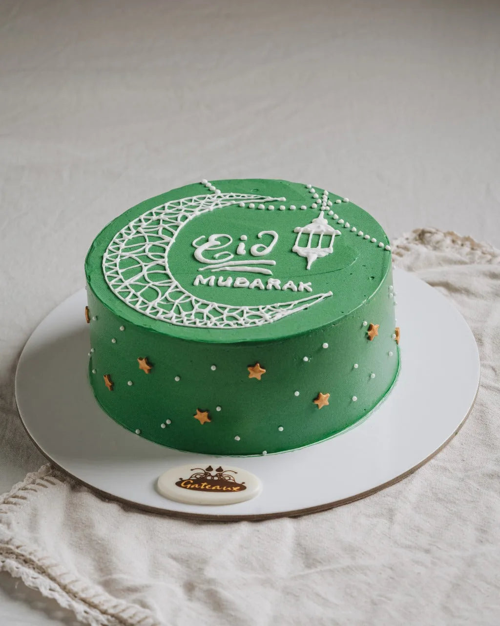 Green cake with 'Eid Mubarak' text on a white plate