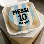 Cake with 'Messi 10 the goat' text in a striped design, likely referencing Lionel Messi, on a marble surface.