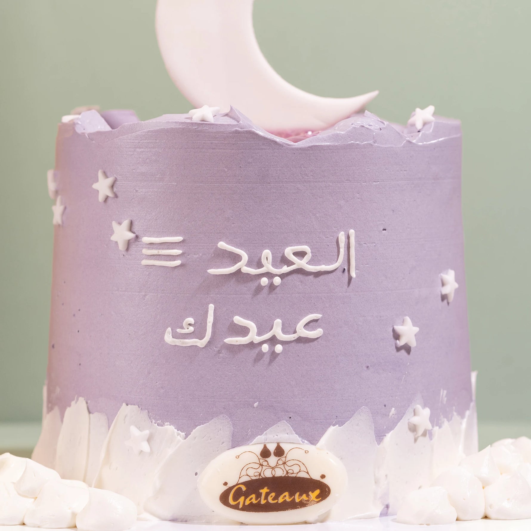 Purple cake with Arabic text and a moon decoration on a light green background