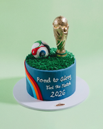 Cake with World Cup trophy and soccer ball on a green grass base with 'Road to Glory' text