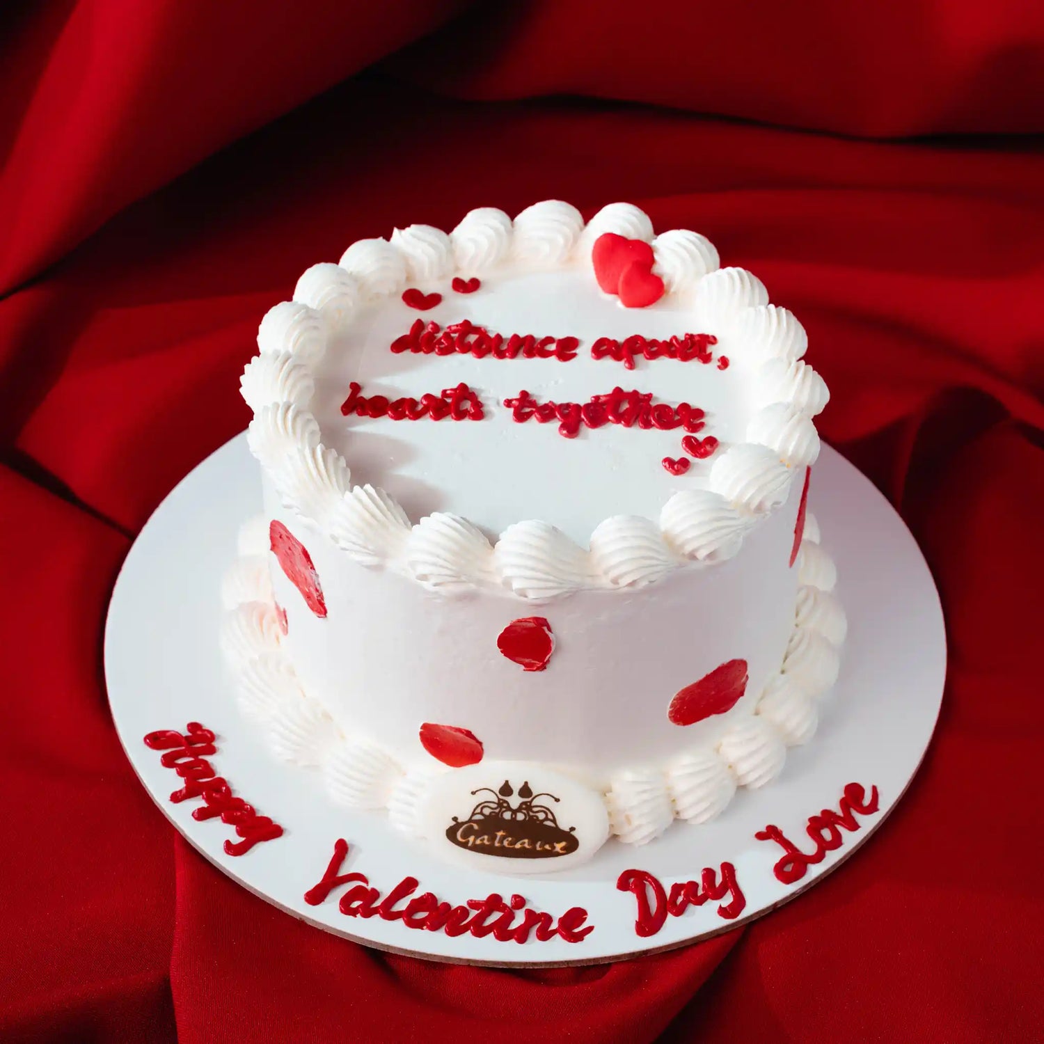 Valentine's Day cake with red hearts and text on a red fabric background