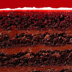 Close-up of a layered chocolate cake with white frosting on a red background